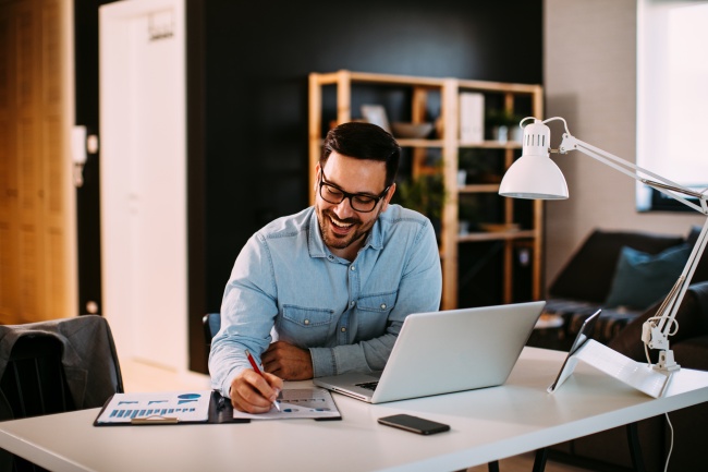 smiling young businessman working on laptop with occupancy charts