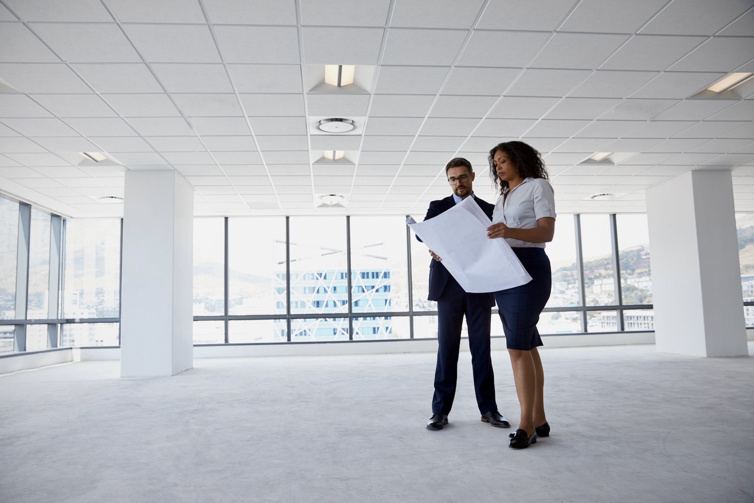 Businesspeople,meeting,to,look,at,plans,in,empty,office