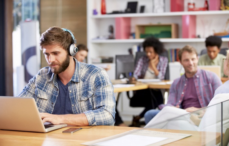 Businessman,wearing,headphones,working,on,laptop,in,office